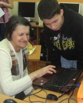 Young volunteers teach seniors to use computers in the library, helping to break down barriers between the generations.