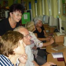 A group of senior people learning internet skills in the library. 