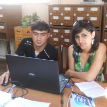 A library trainer shows a young woman trainee how to use a computer to access the internet.