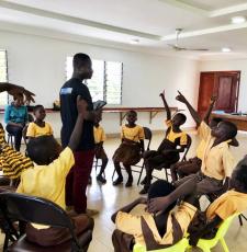 Digital skills training at a school in Ghana. The children are sitting in a circle, interacting with a teacher. 