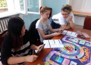 children playing a board game called cash flow at a table in the library