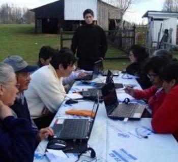 Farmers around a table, learning computer skills.