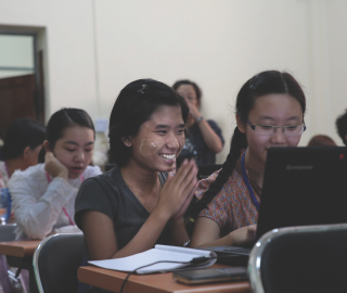 Students learn to use e-resources at the University of Yangon. Smiling students learning to use computers in University of Yangon.