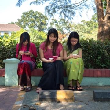 Three young women students from Myanmar using mobile phones to access e-resources.