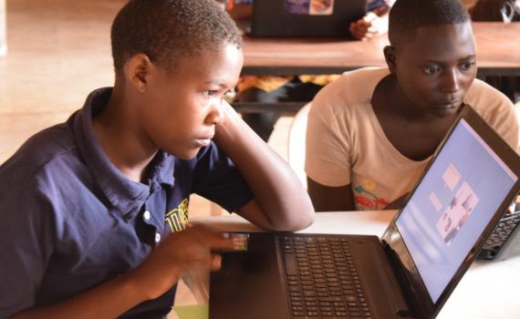 Young women learning to use laptop computer in a library.