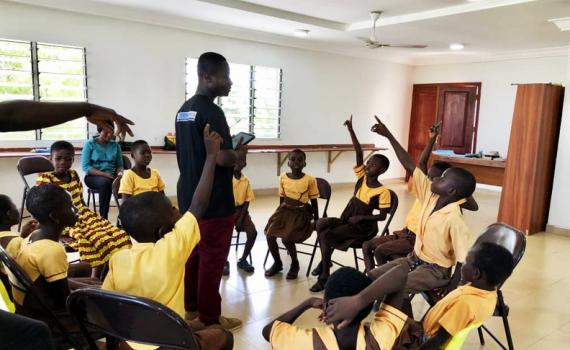 Digital skills training at a school in Ghana. The children are sitting in a circle, interacting with a teacher. 