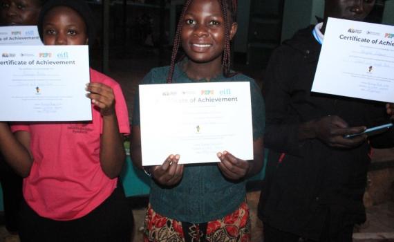 Three young ICT graduates from Kawempe Youth Centre and Community Library show their certificates of achievement.