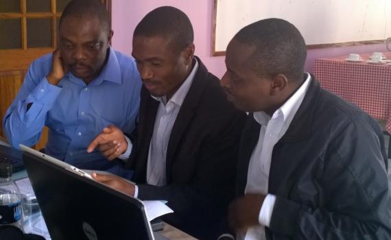 three delegates working at a computer during an oa policy formulation workshop in 2015