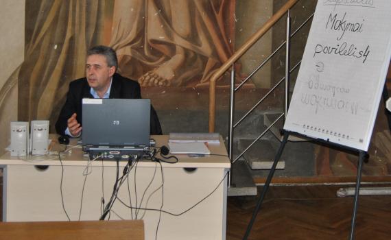 Representative of the Šiauliai County Police discussing online police services with trainees in the library.