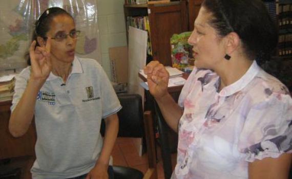 A  library trainee practises sign language with a librarian.